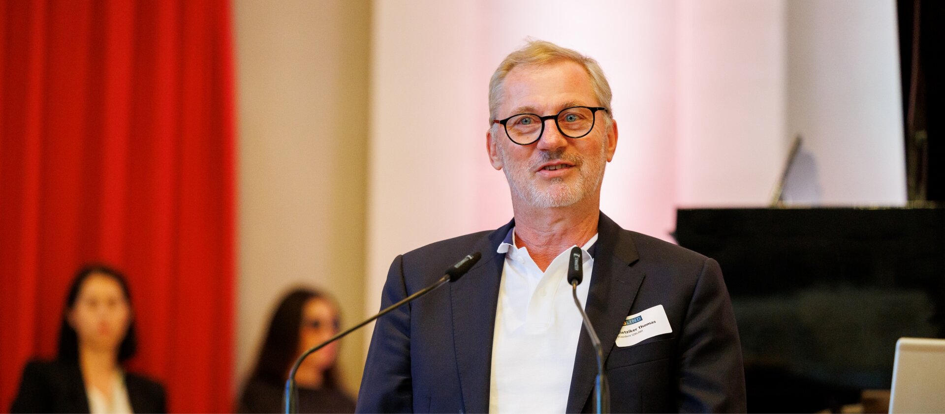 Thomas Dietziker spricht an einem Rednerpult mit zwei Mikrofonen.